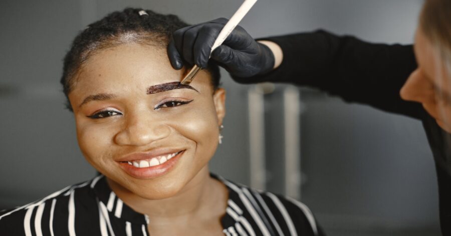 makeup artist painting on eyebrows on a client